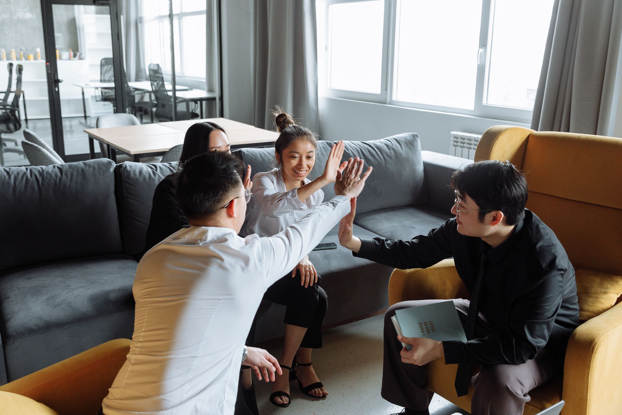 Asian colleagues celebrating with a high five in the office